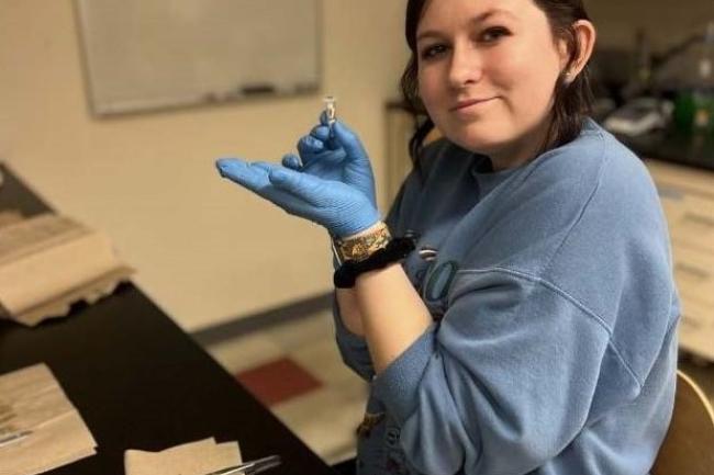 Student holds DNA sample while sitting in science lab